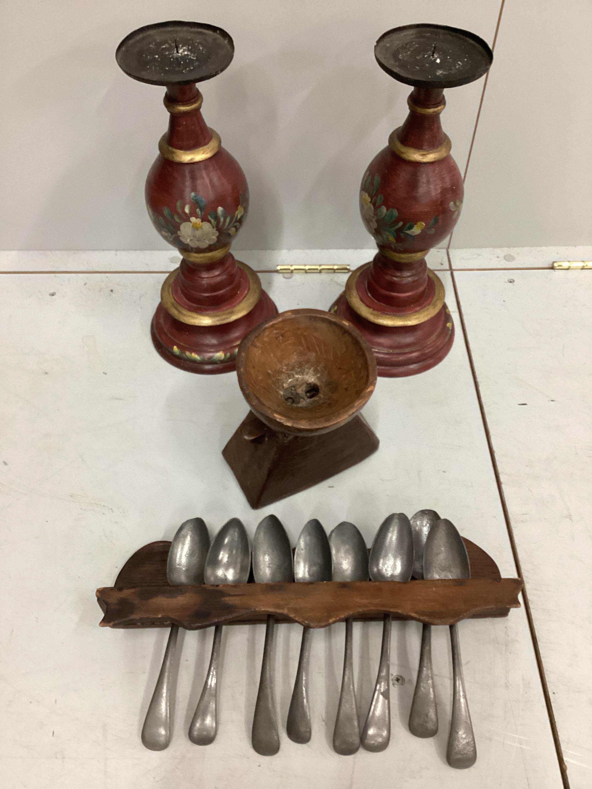 A pair of painted baluster pricket candlesticks, height 39cm, a spoon rack, pewter spoons and a carved wood seed spreader